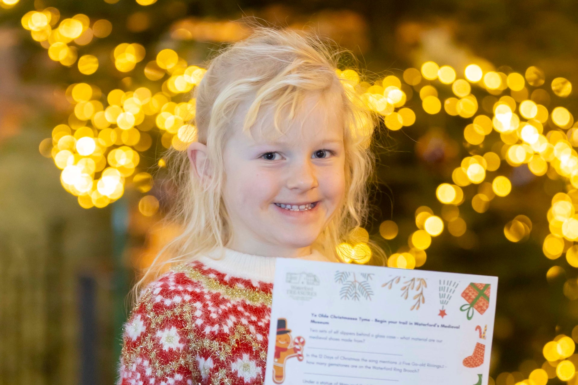 A smiling young girl holding up a piece of paper