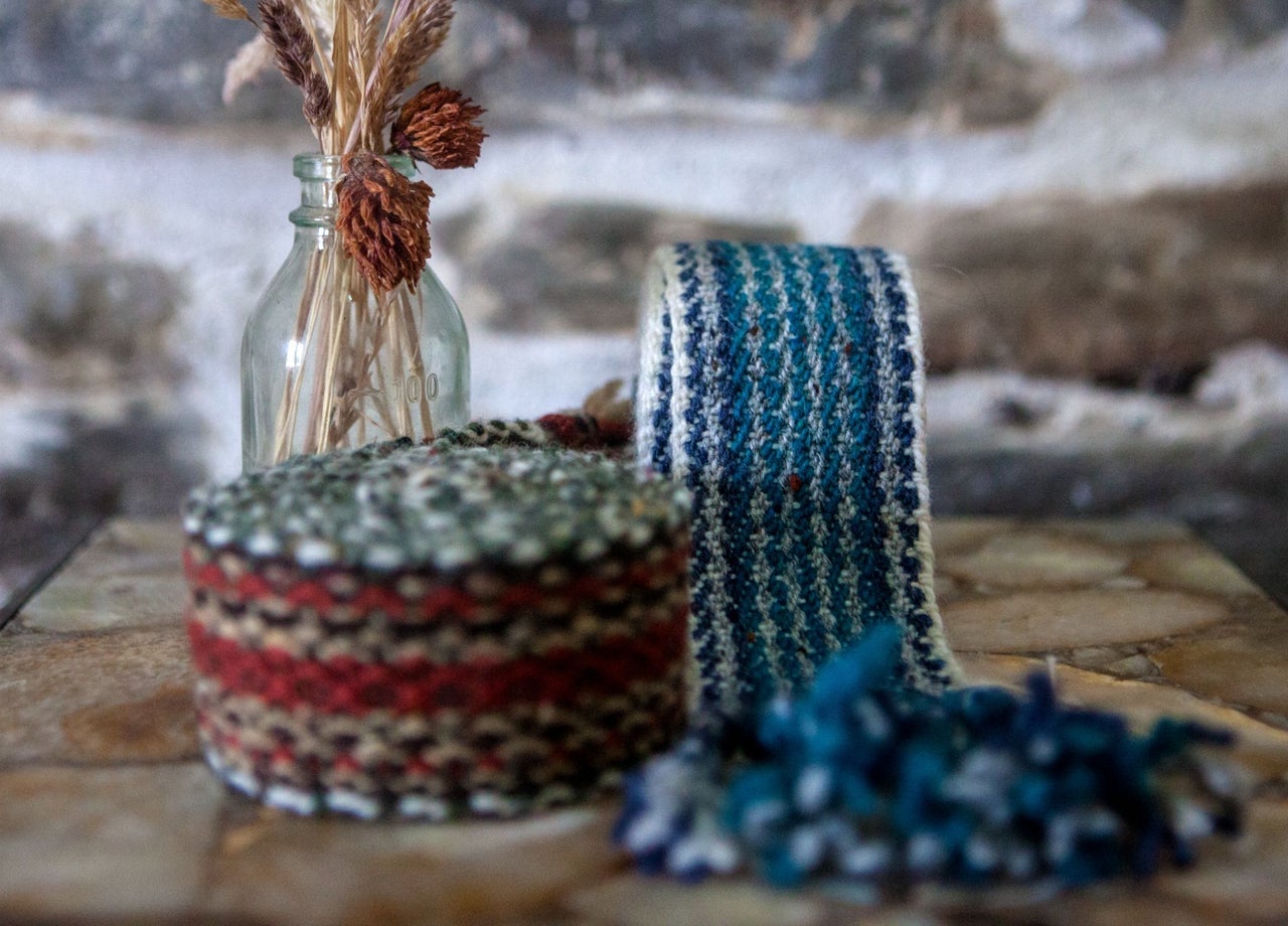 Blue and red tone crios belts displayed alongside a glass bottle