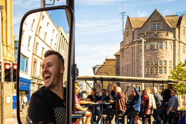 A pedal tour bike on a sunny city street with passengers chatting 