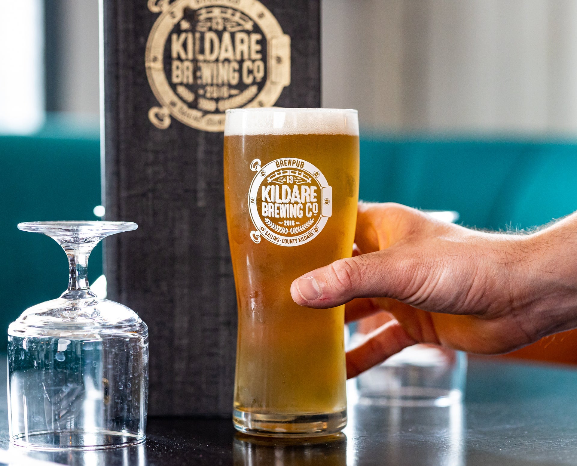 A pint glass of pale ale with the logo of Kildare Brewing Company on it