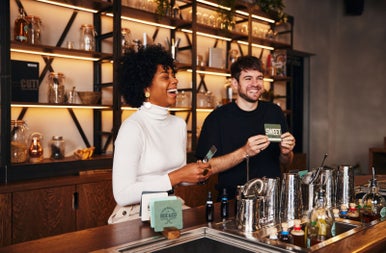 Two people standing behind a bar laughing