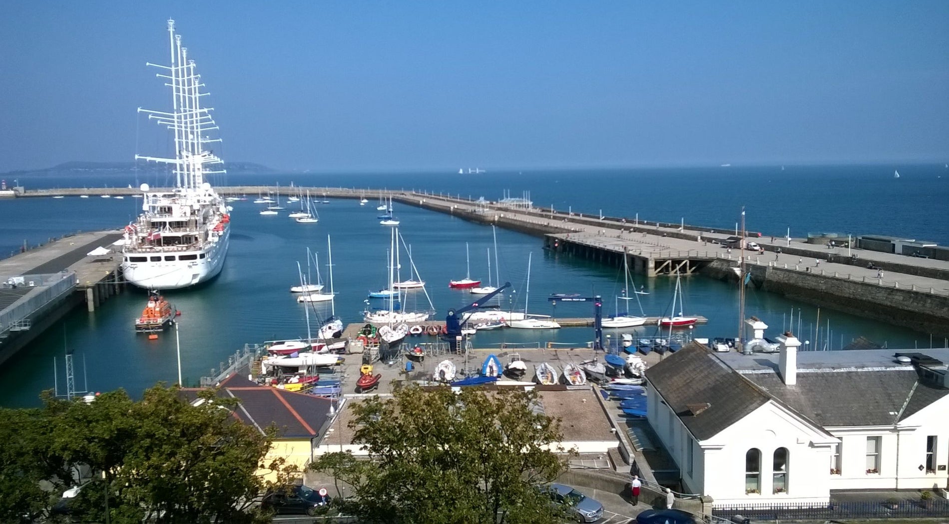 A view of a harbour with small boats and one large ship with tall masts