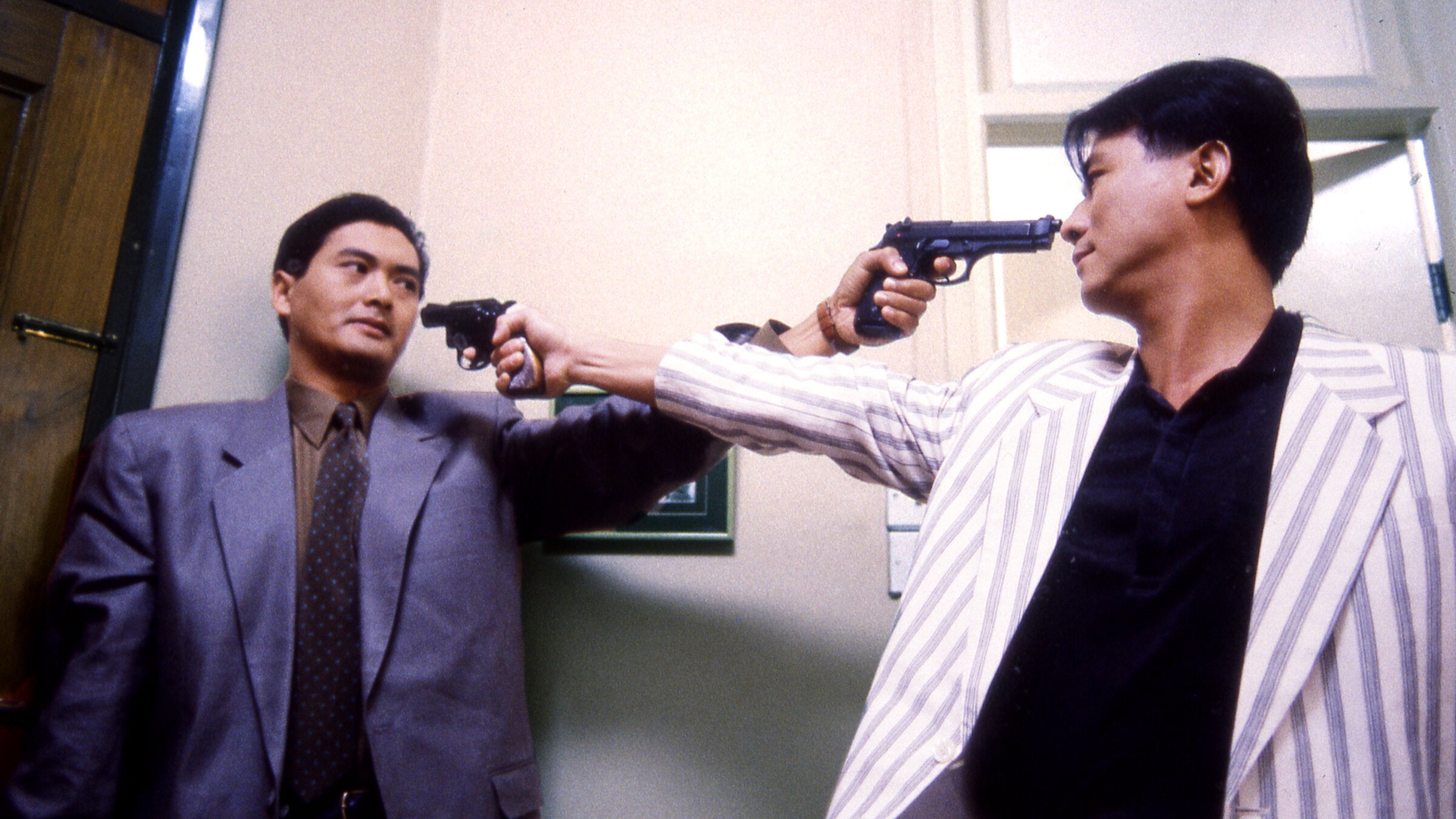Two men pointing pistols at each other.