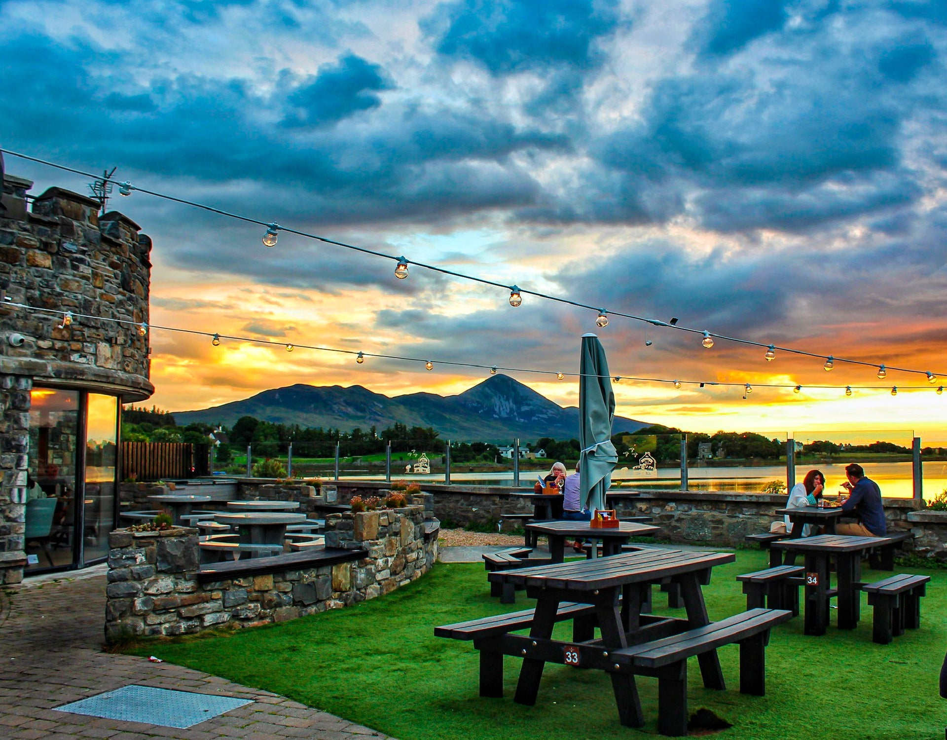 Sunset behind the Tower Garden with customers seated at wooden picnic style benches