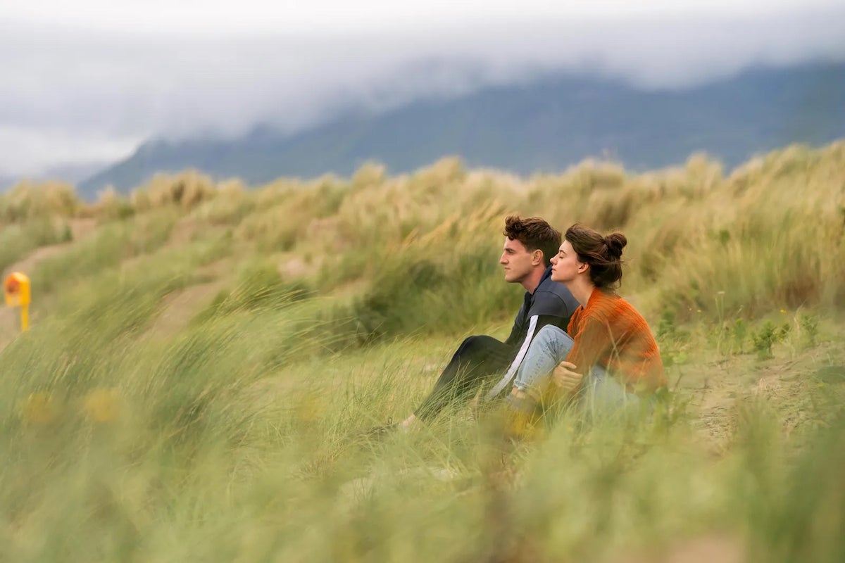 A scene from the series 'Normal People', featuring a couple, male and female sitting amongst the marram grass on a beach in county Sligo.