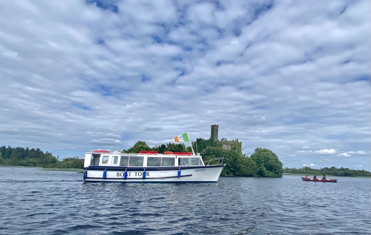A tour boat cruising by an island on a lake with a castle ruin