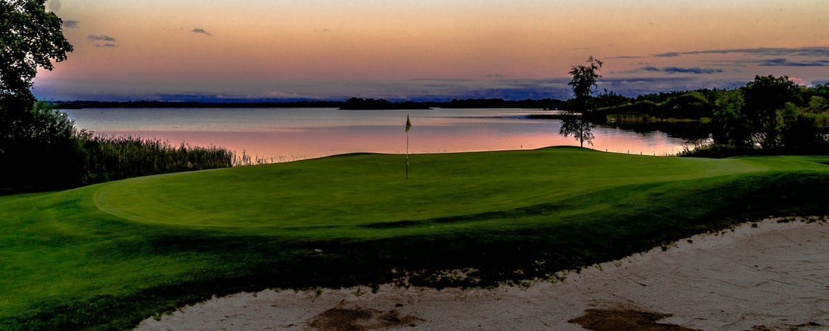A golf course beside a lake at sunset