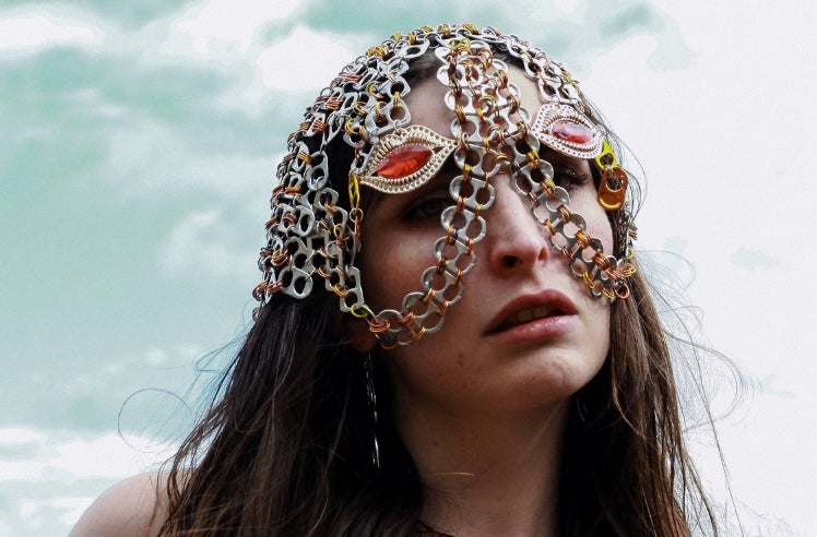 A person with long dark hair wearing a head and partial face covering made from interlinked chains.