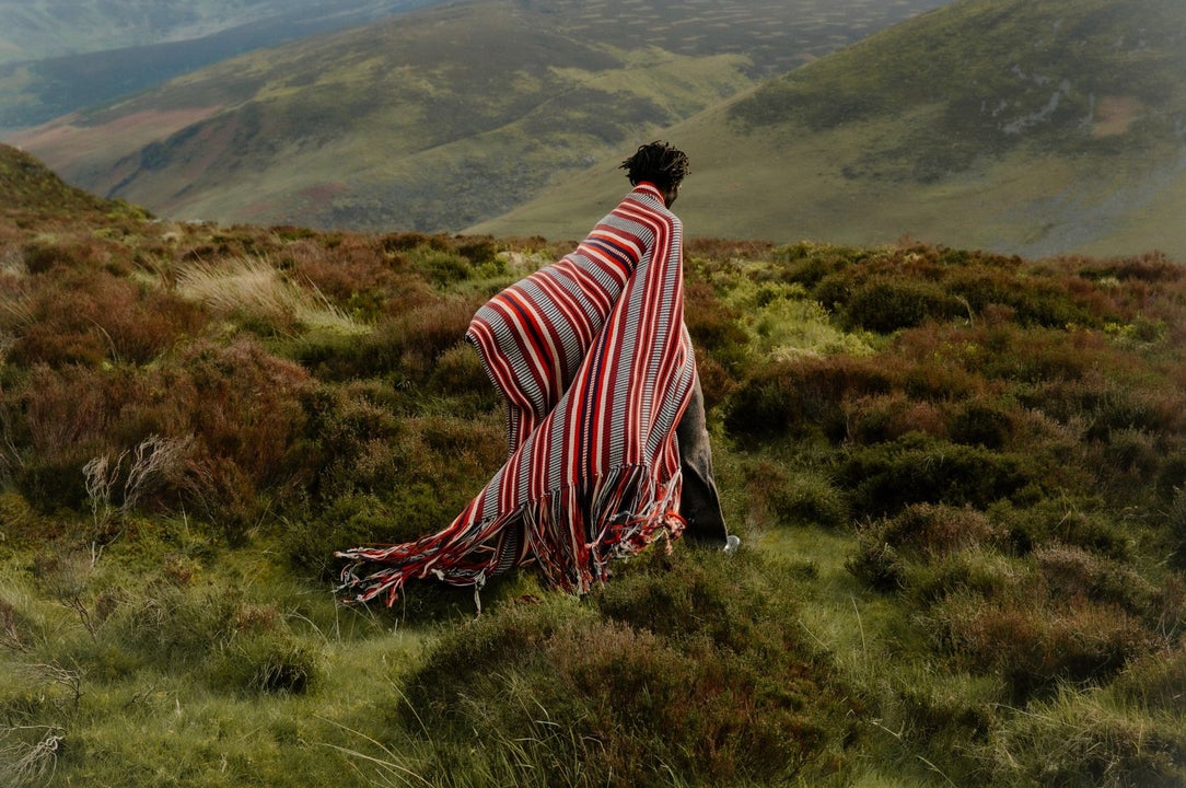 A person wearing a large wrap around and colourful shawl type of clothing in the outdoors 