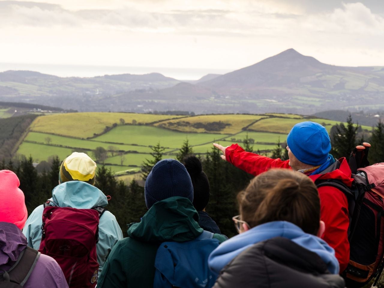 A hiking guide points out a distant feature to a group of hikers