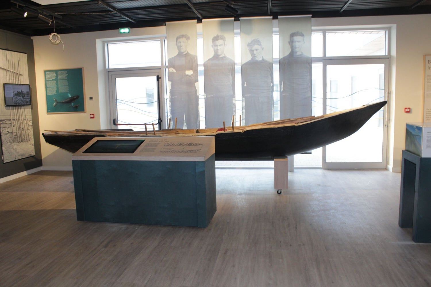 A display featuring a currach boat with images of fishermen in the background