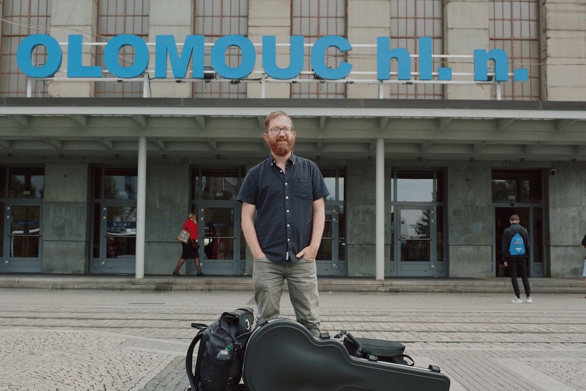 A master storyteller, Niall Connolly, a man standing in front of a building with guitar case and bags