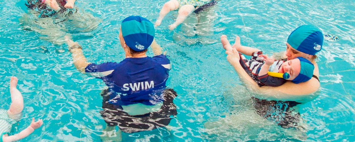 A swimming instructor with clients in the swimming pool