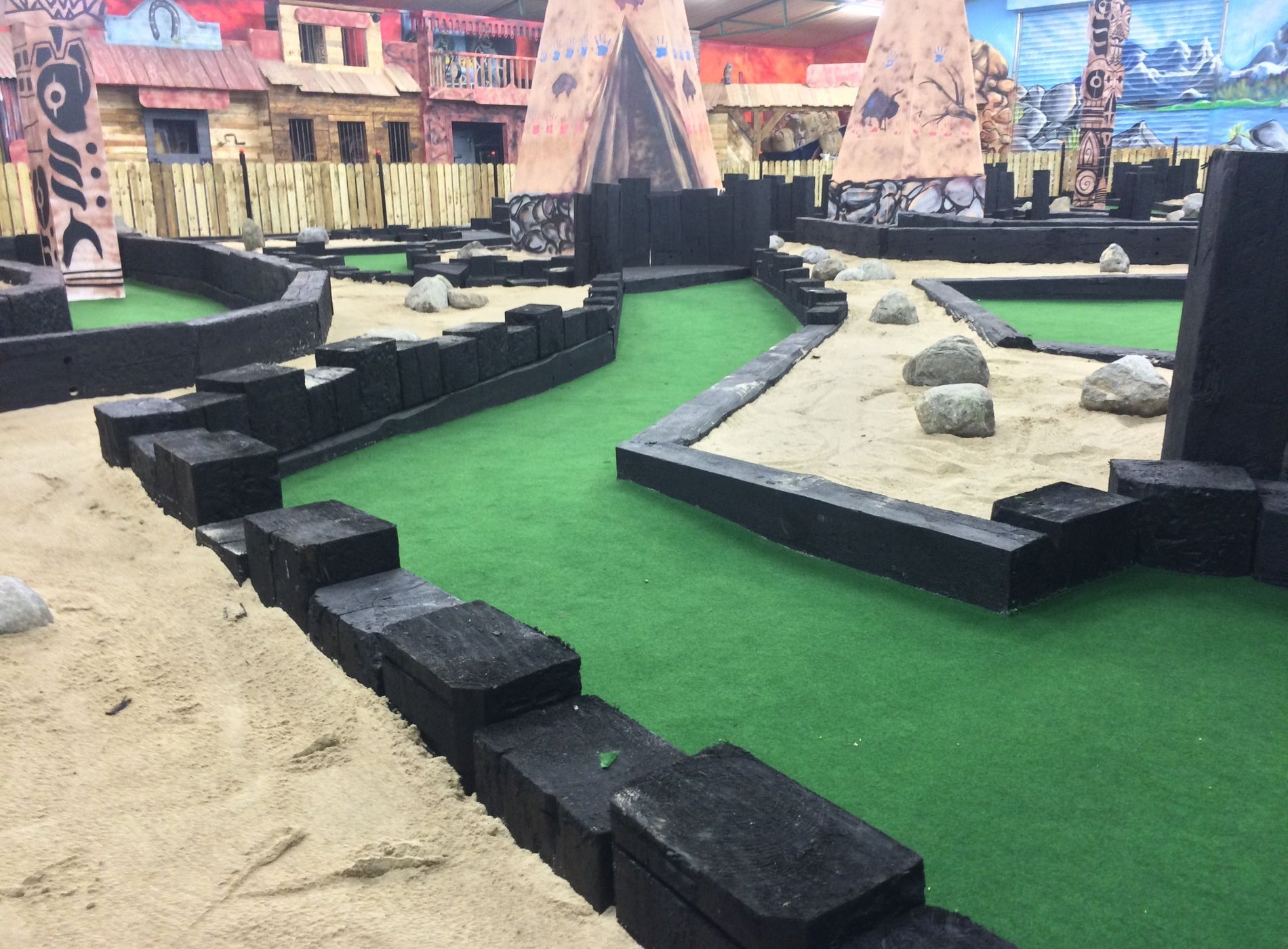 An indoor play area for kids with sand and small buildings to explore