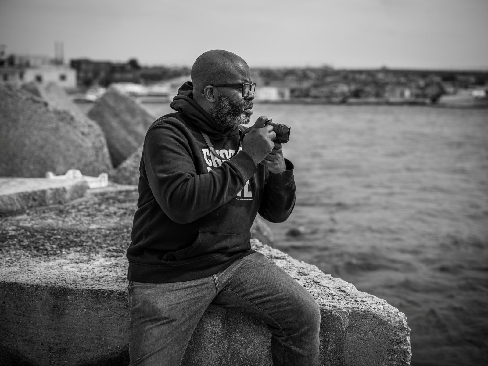 A man with a camera next to a body of water.