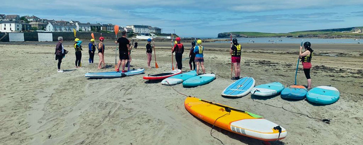 A group of paddleboarders practising on the sandy shore