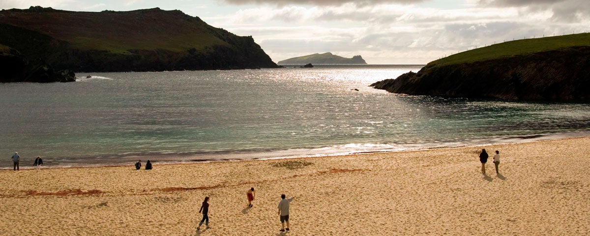 People walking in the distance on Clogher Beach in evening light