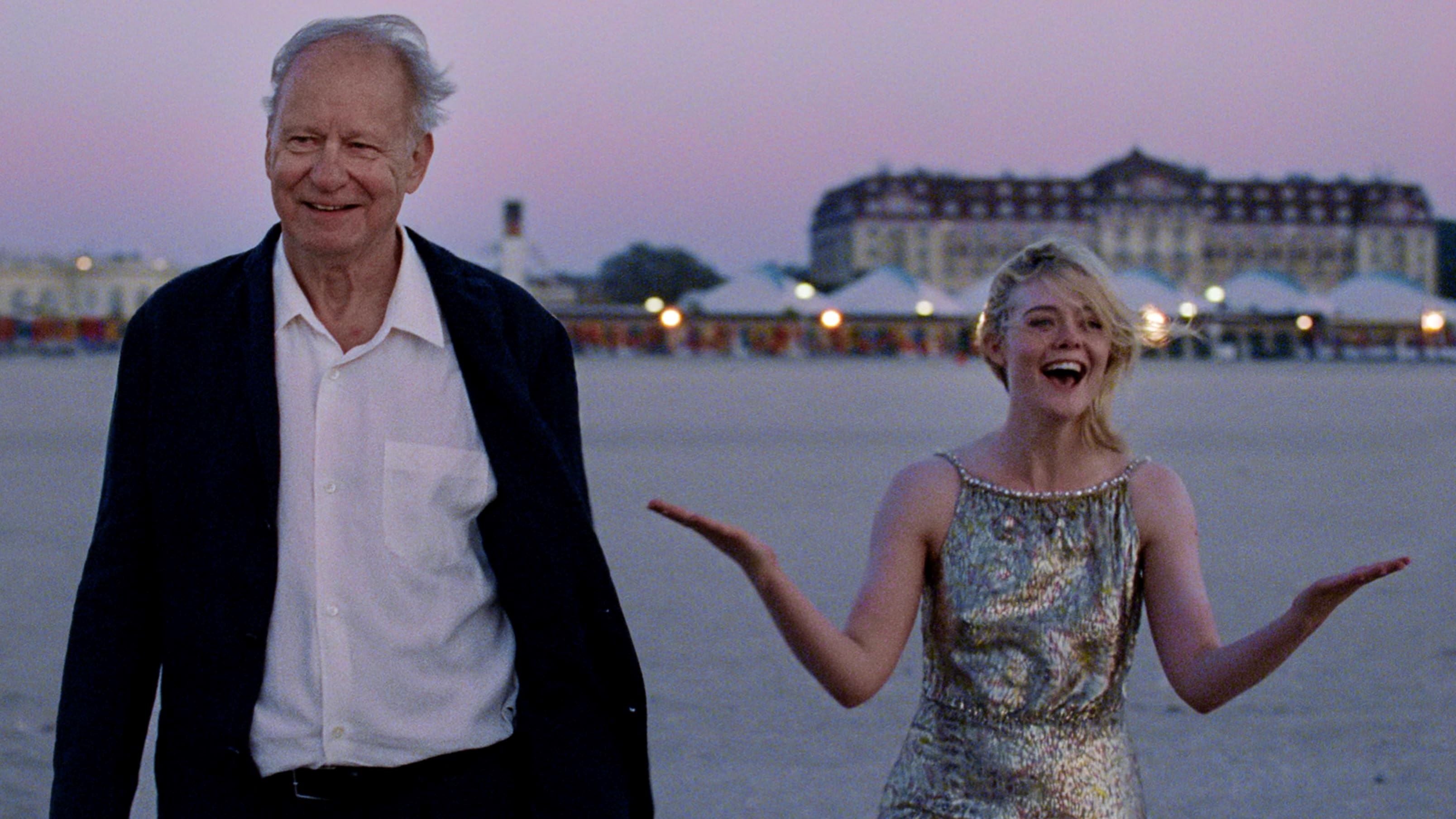 A joyous old man and young woman are on a beach.