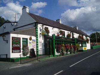 Exterior view of The Merry Ploughman Pub a white building with green trim and shopfront