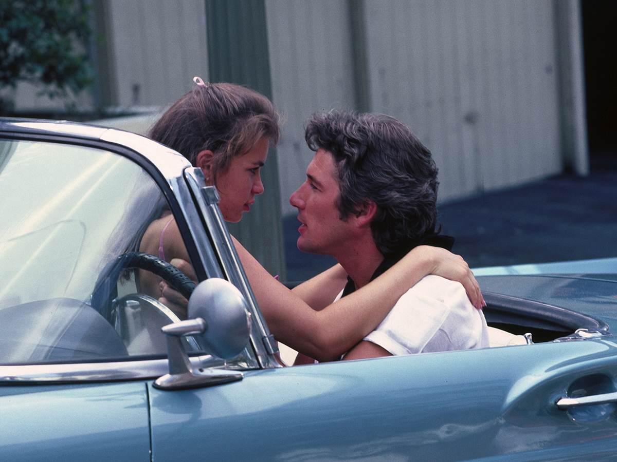 A man and a woman in a car, staring lovingly into each other's eyes.