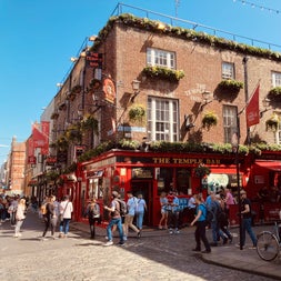 Red and black painted exterior of the temple bar pub with people walking around outside