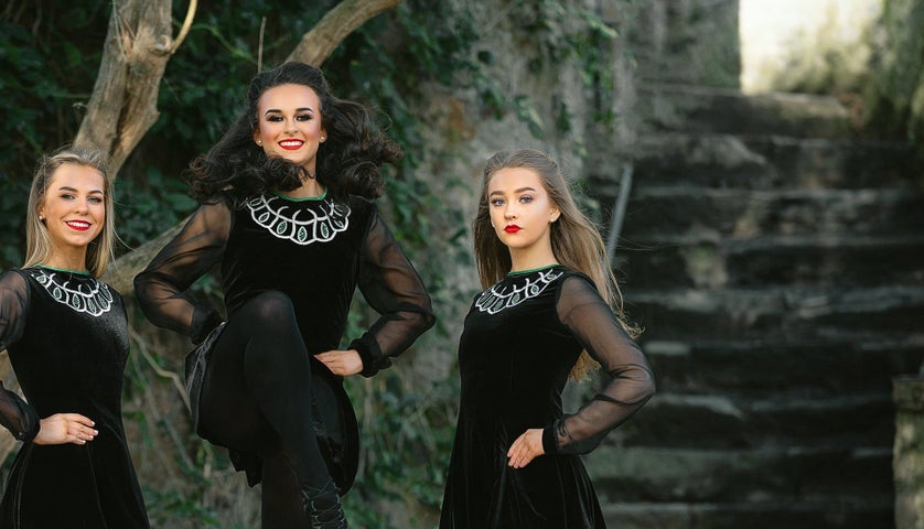 Three Irish dancers wearing Celtic dress performing with Twist of Irish