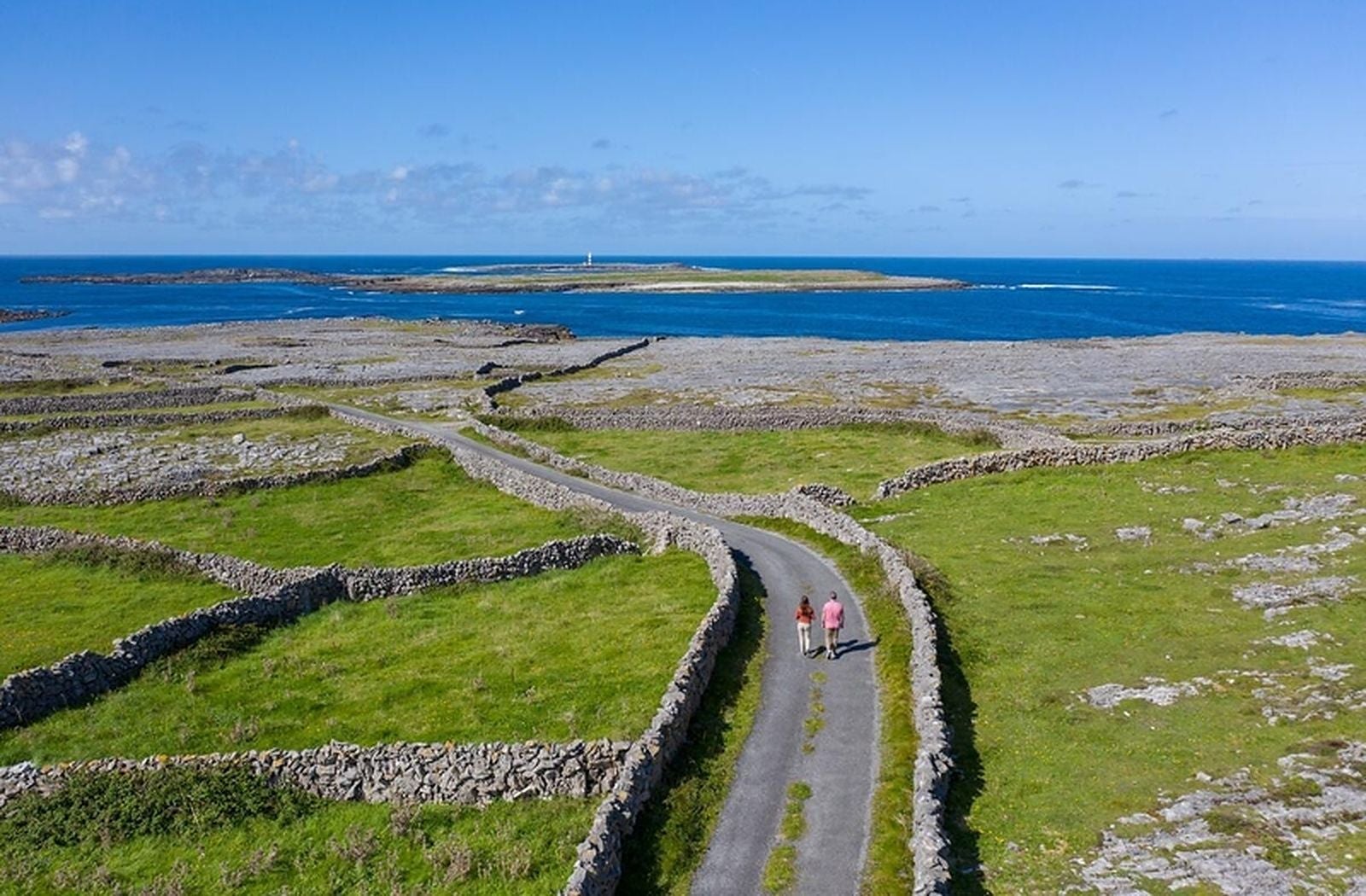 A road lined with stone walls leading to the sea