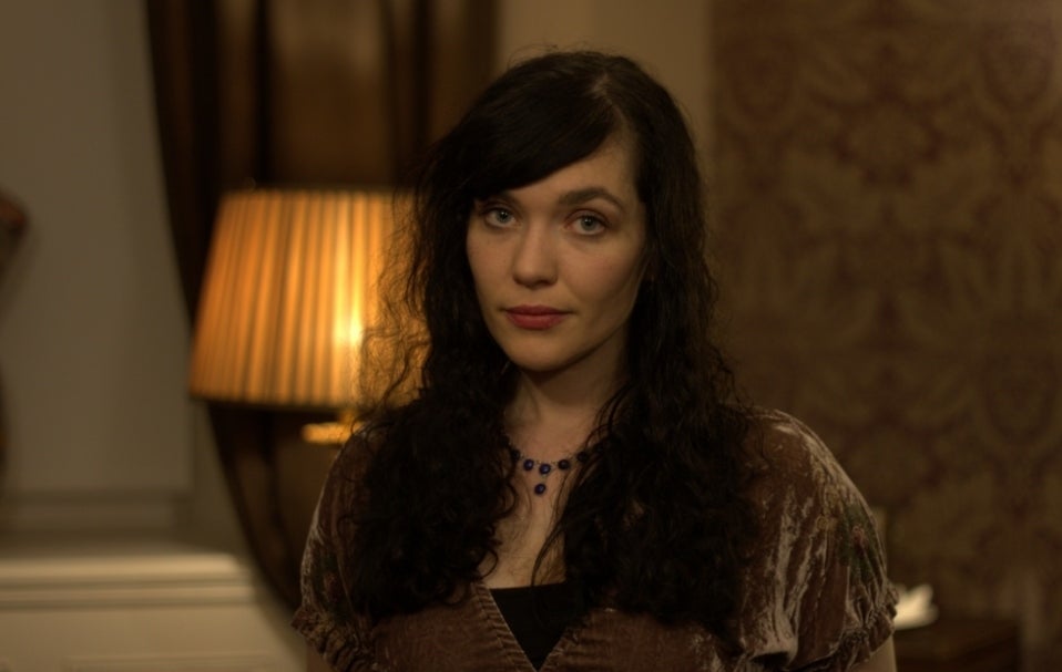 A woman sat beside a dimly lit orange lamp.