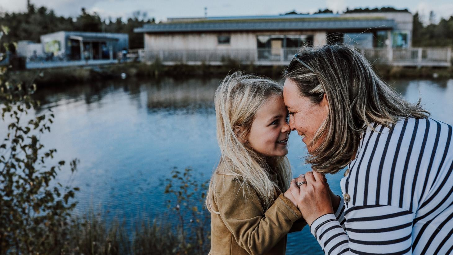Woman and child embracing in front of a body of water at Lough Boora Discovery Park in Offaly