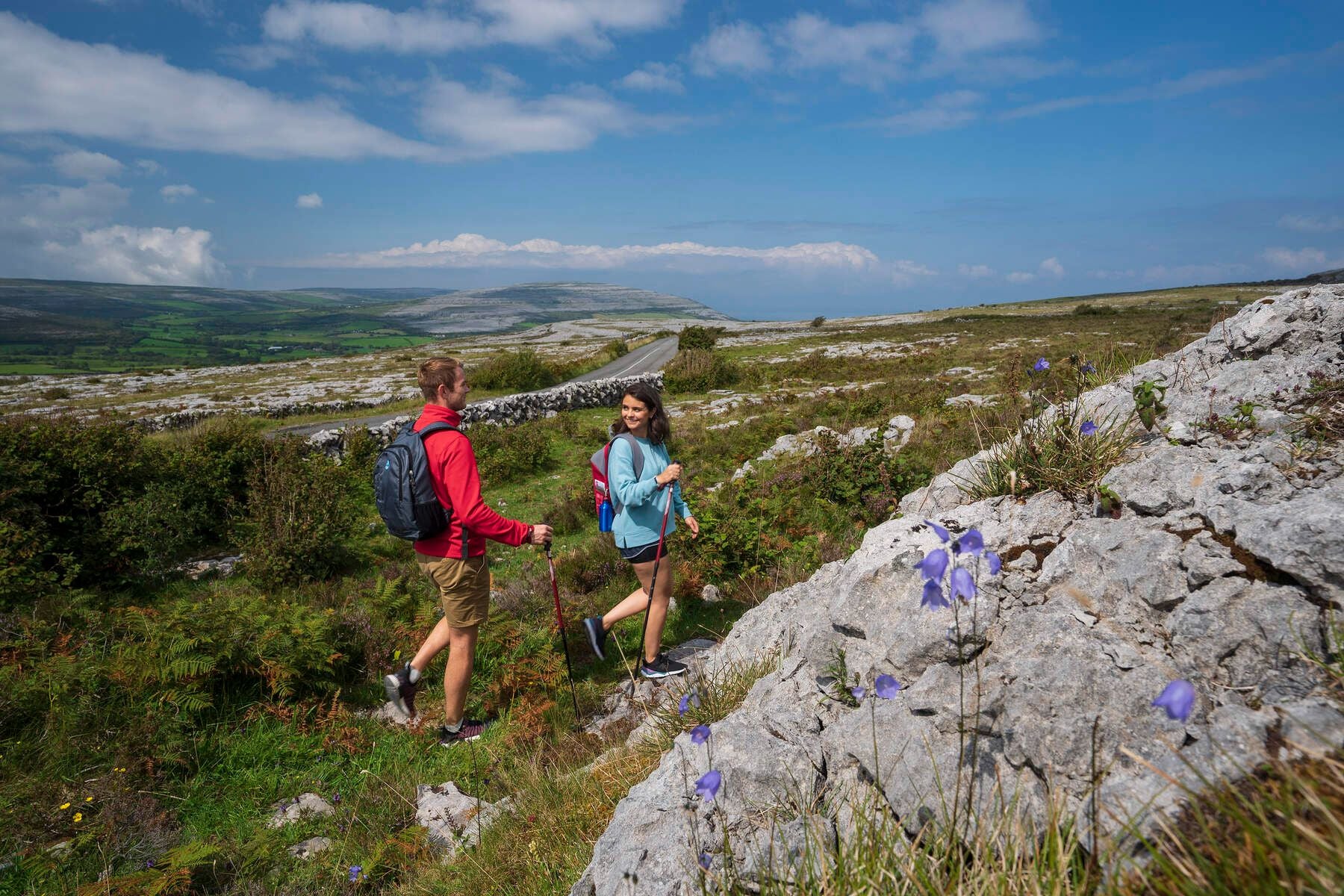 Two people with backbacks walking along a rocky landscape