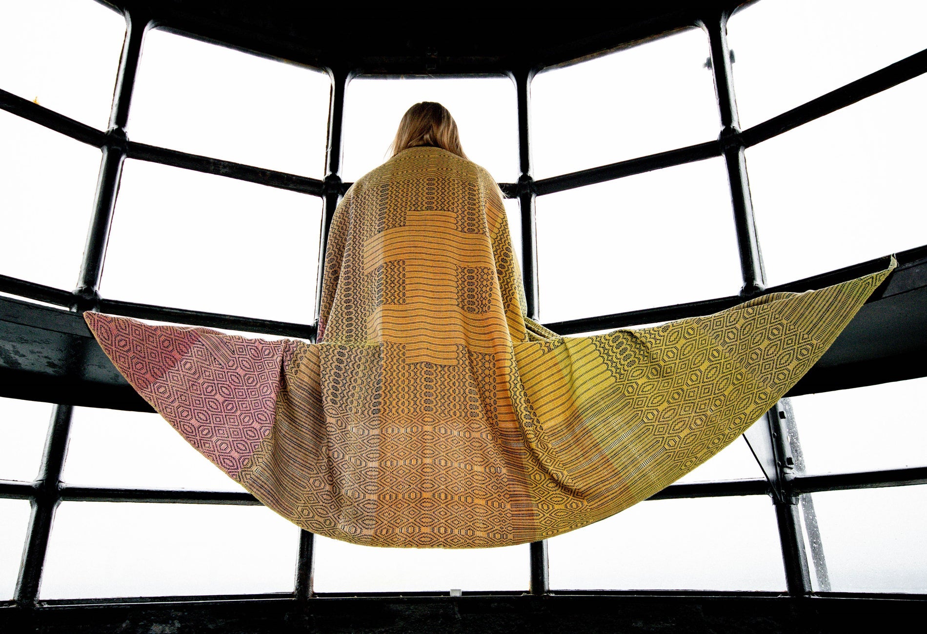 Person modelling a colourful scarf that is spread out over a bench