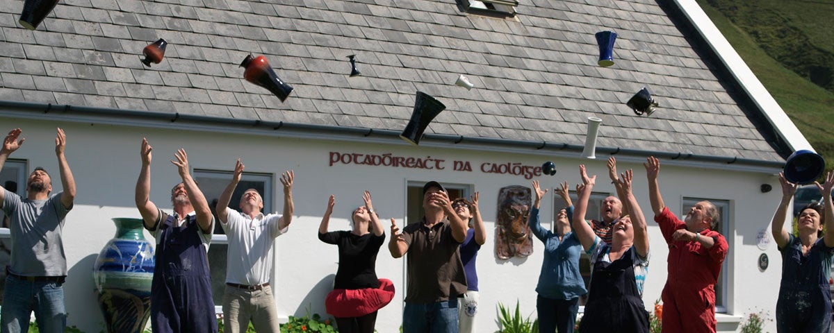 People throwing pottery in the air outside Louis Mulcahy Pottery