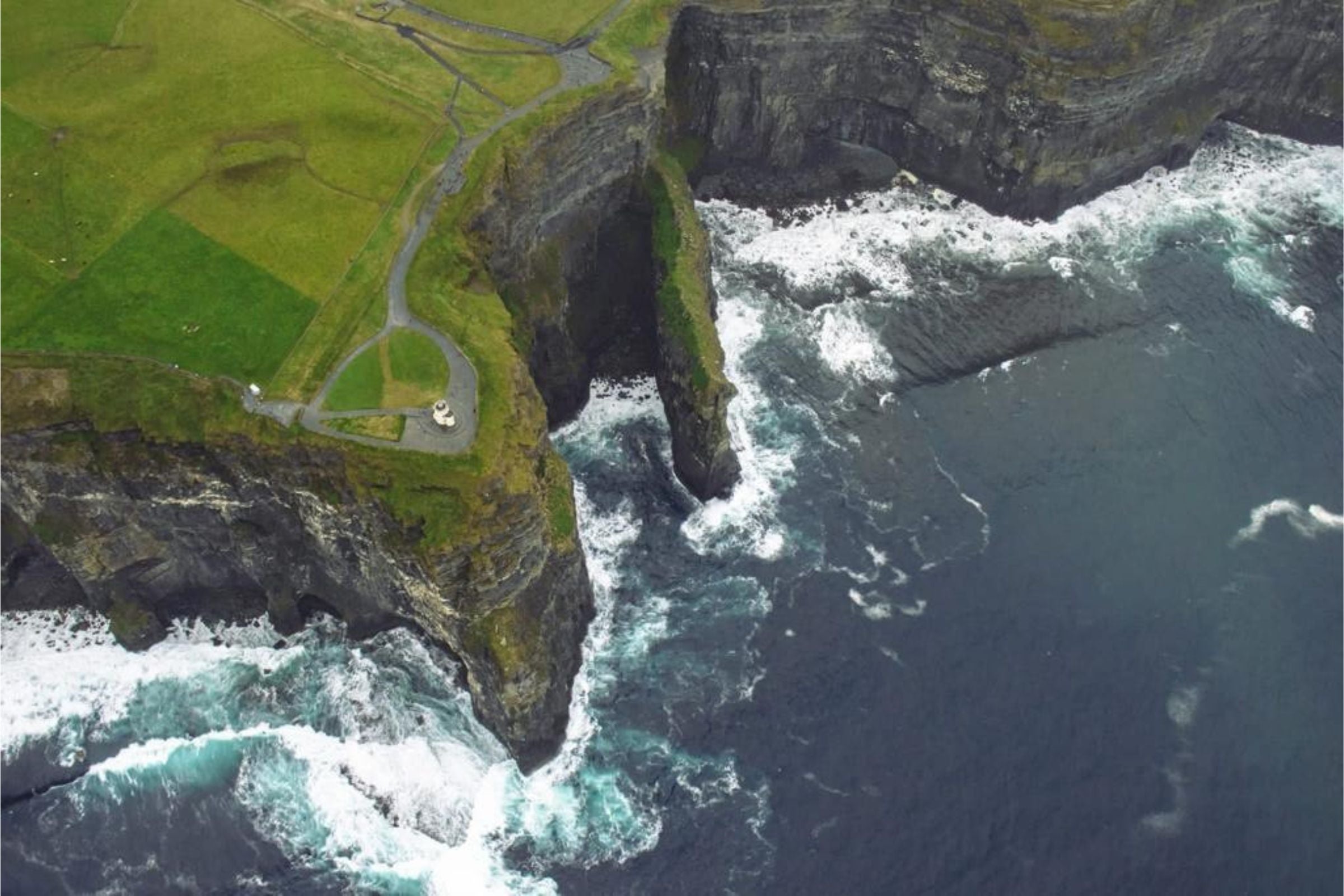 Helicopter view of the Cliffs of Moher with a glimpse of O Briens Tower