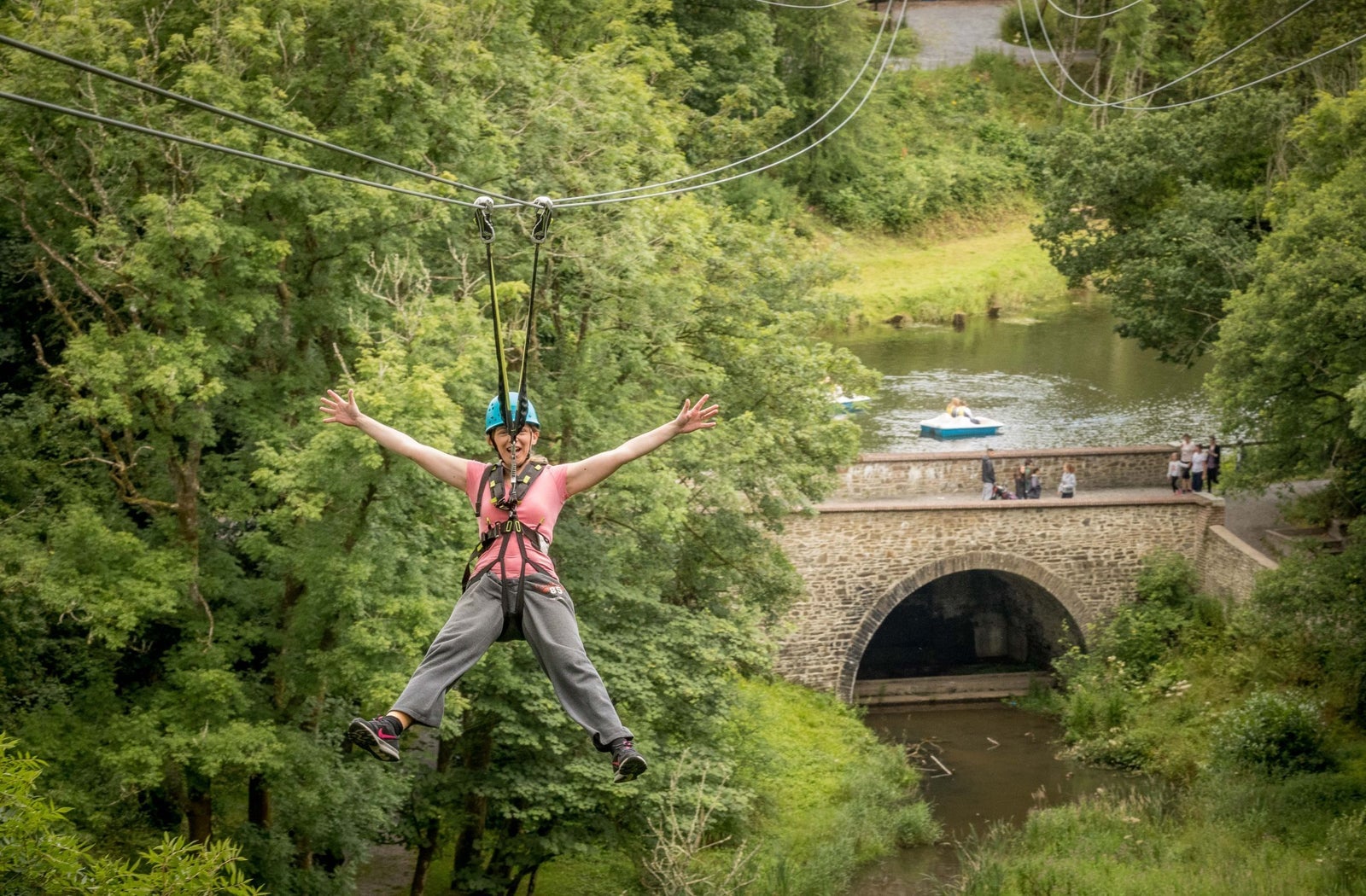 A person on a zipline wearing a harness and helmet
