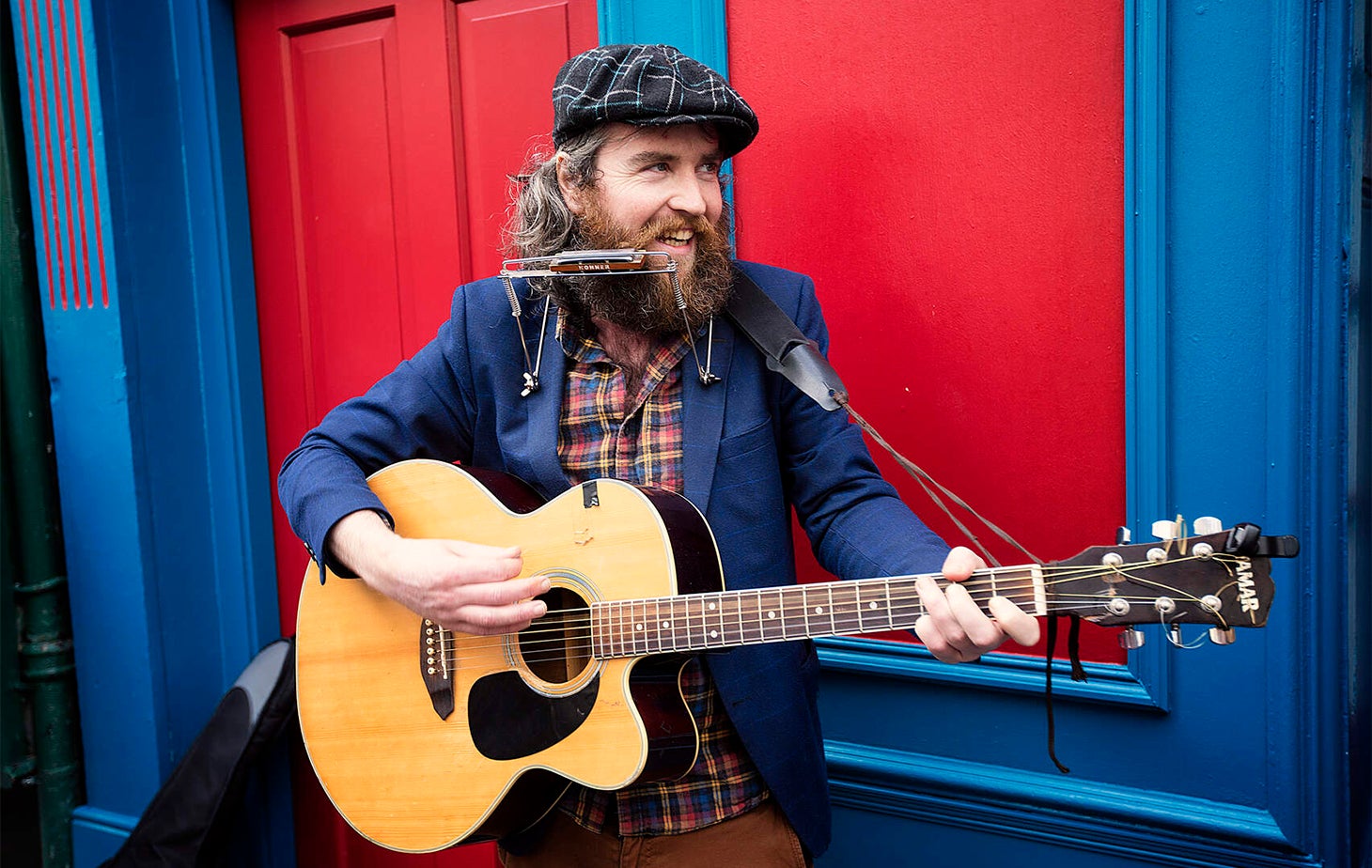 Man playing the guitar and the harmonica.