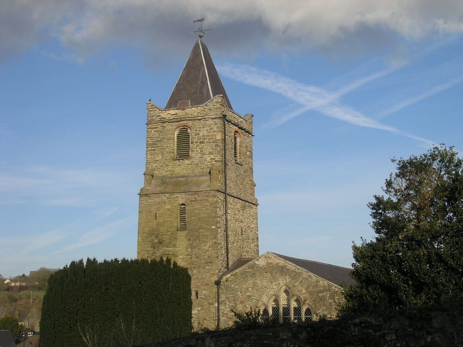 Church tower on a sunny day behind trees