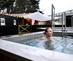 A lady sitting in the cold plunge pool at The Hot Box Sauna Inchicore