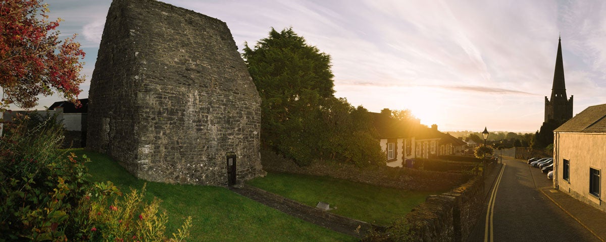 A small ancient stone building on a street lined with houses