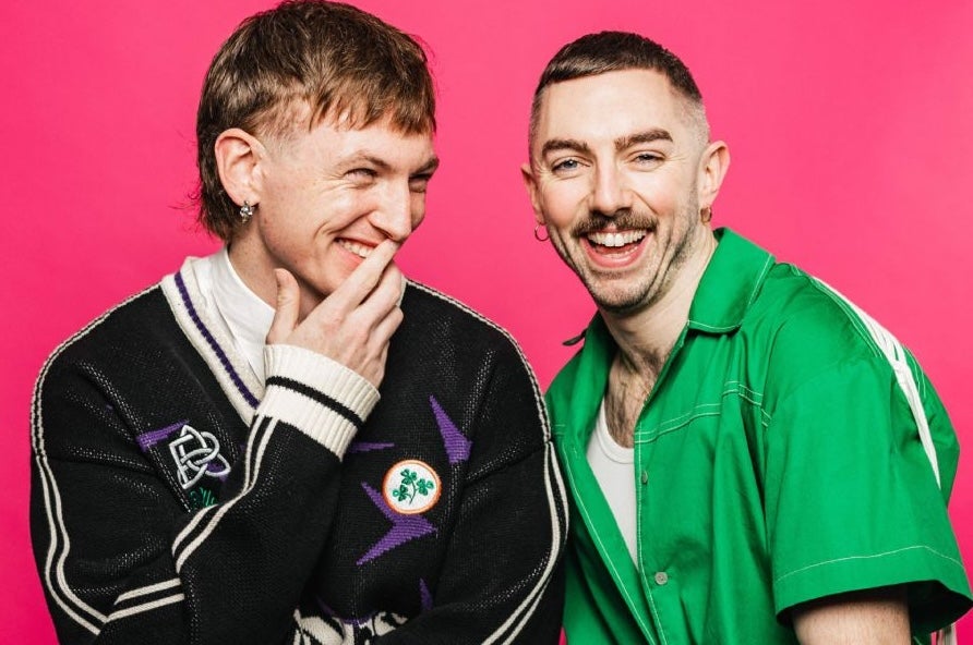 2 laughing men against bright pink background.