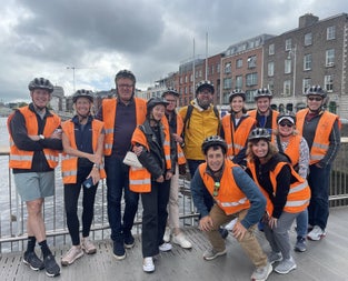 Group of people in orange high visibility vests posing for a picture on a bridge