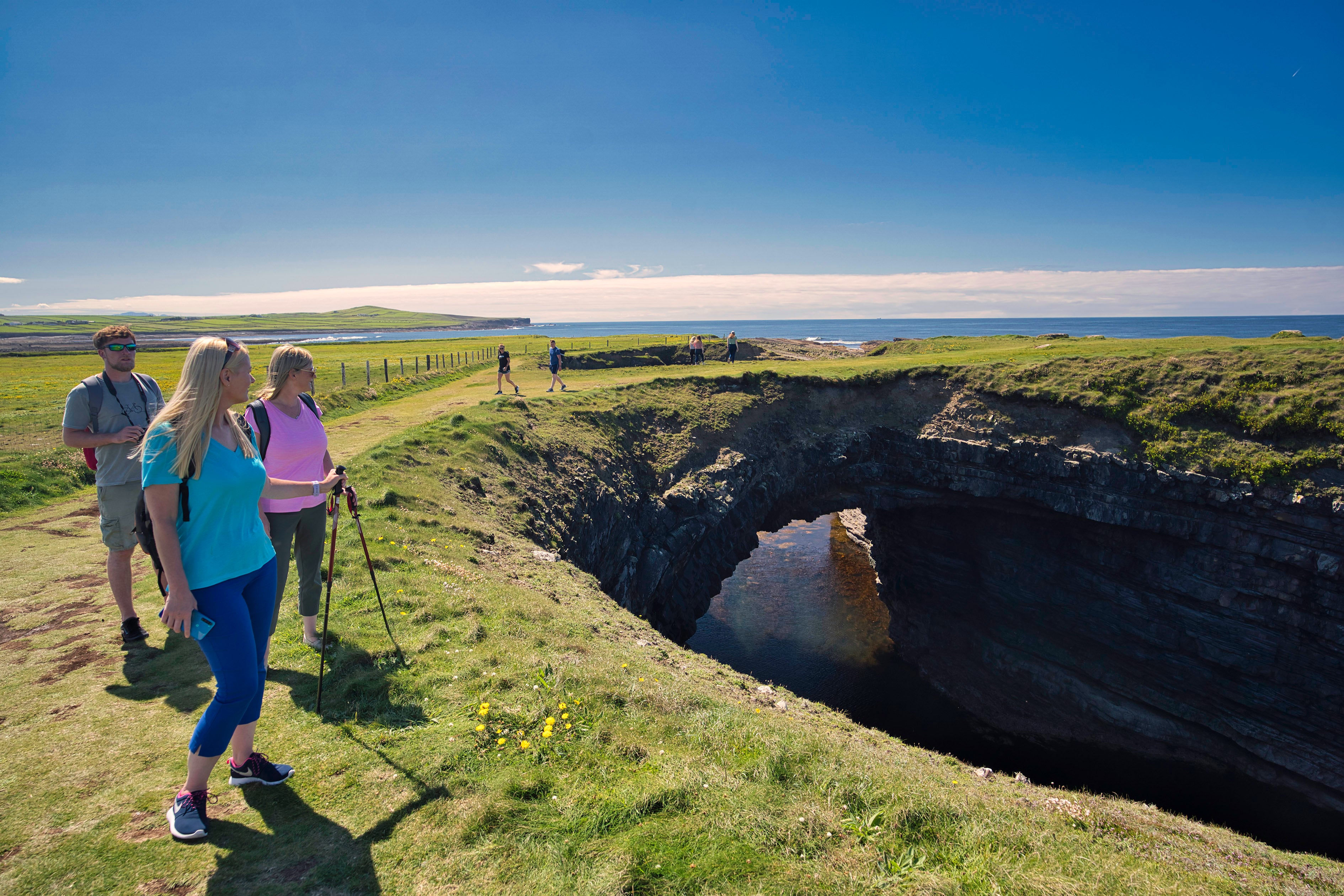 Three people admiring the Bridges of Ross in County Clare.