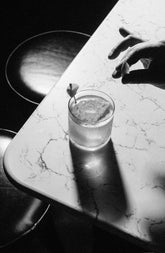 A cocktail in a short glass on the corner of a white marble bar counter