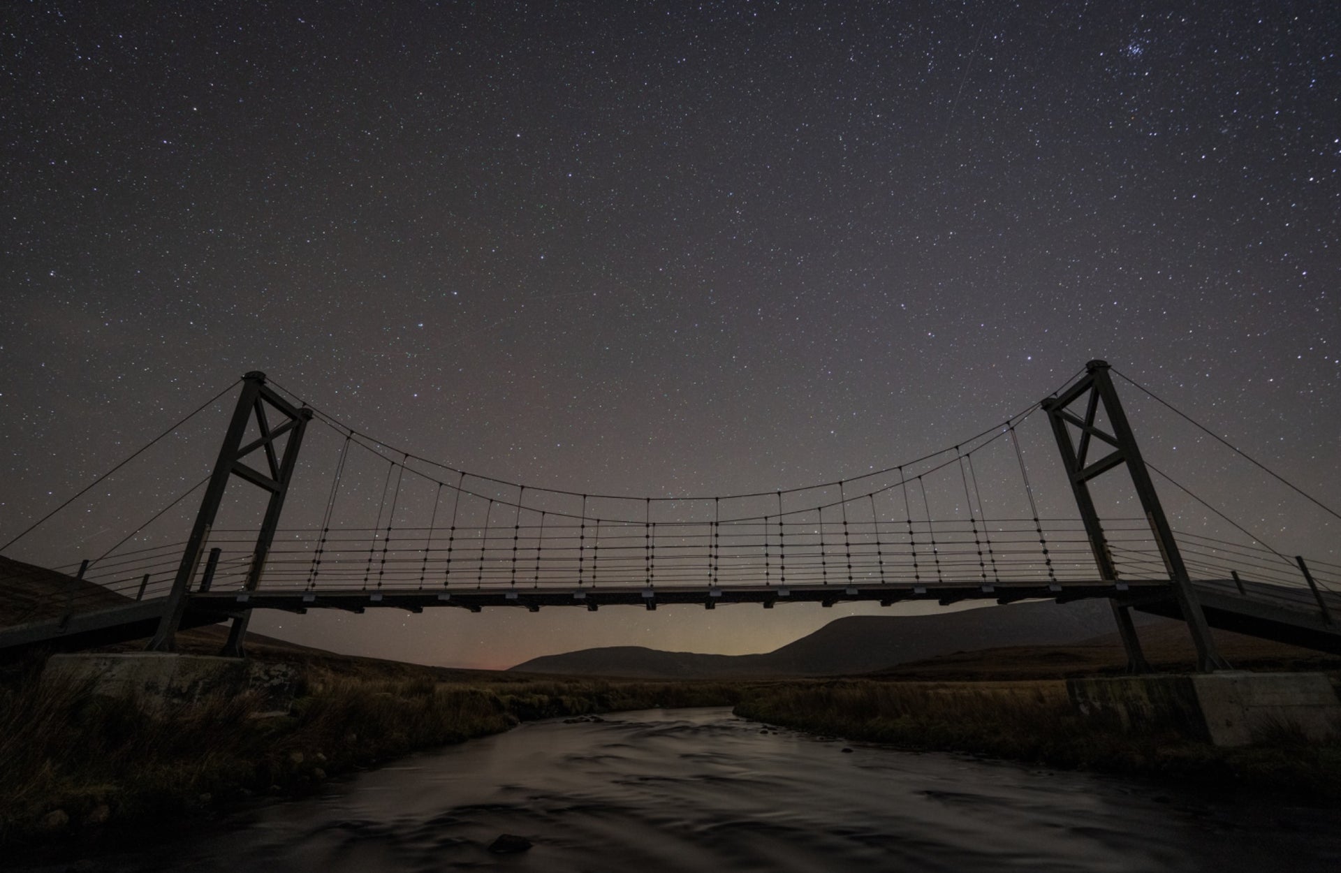 A darkened sky with stars behind a raised footbridge