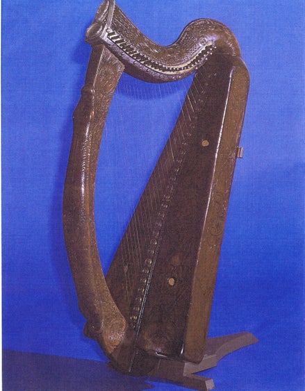 An old dark wooden harp against blue background.