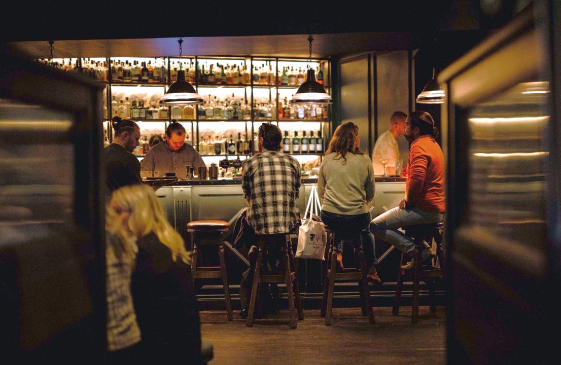 People sitting on stools at a bar in low light