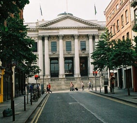 A street view of Dublin City Hall framed by city buildings and trees