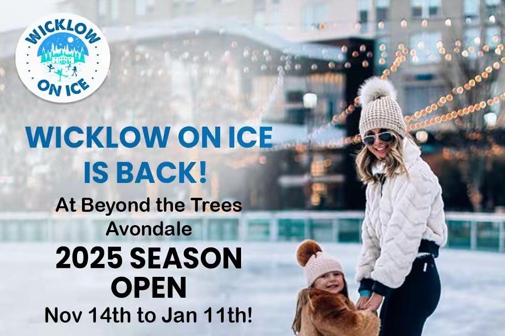 A adult and small child on an ice rink in wooly hats.