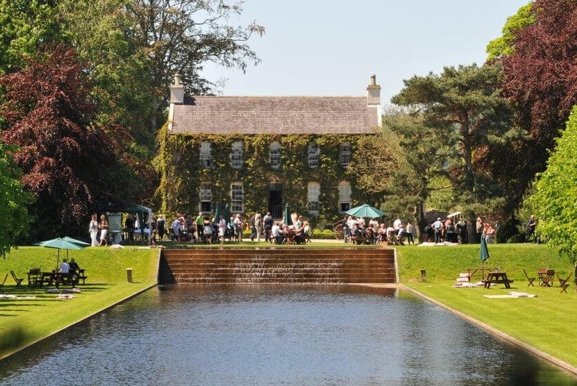 Festival of Gardens & Nature 2026, view across a man made square pond looking at an old house in the distance.