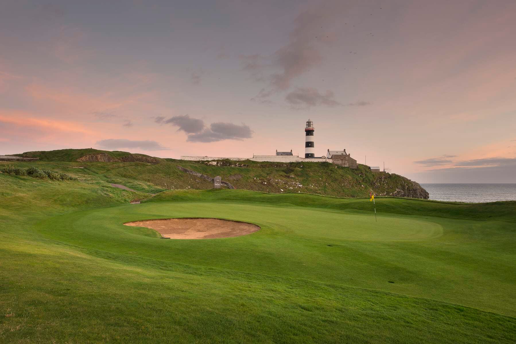 A golfer after putting with Kinsale lighthouse in the distance.