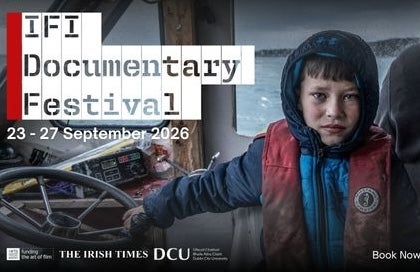 an anxious looking boy in dirty coat holding the wheel of a small boat